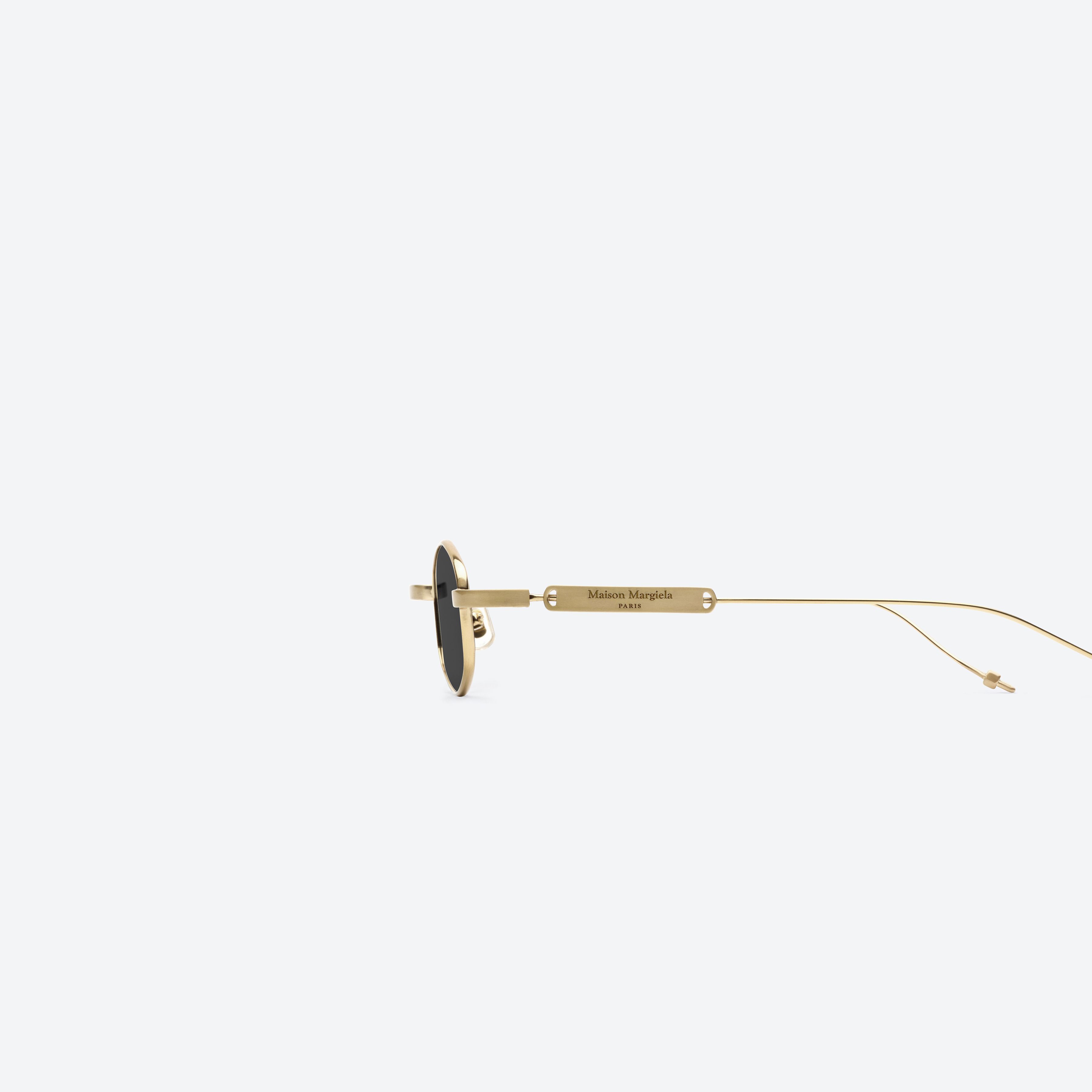 A detailed left view of Gentle Monster Maison Margiela - MM218 A030(G) Gold Metal framed Oval glasses.