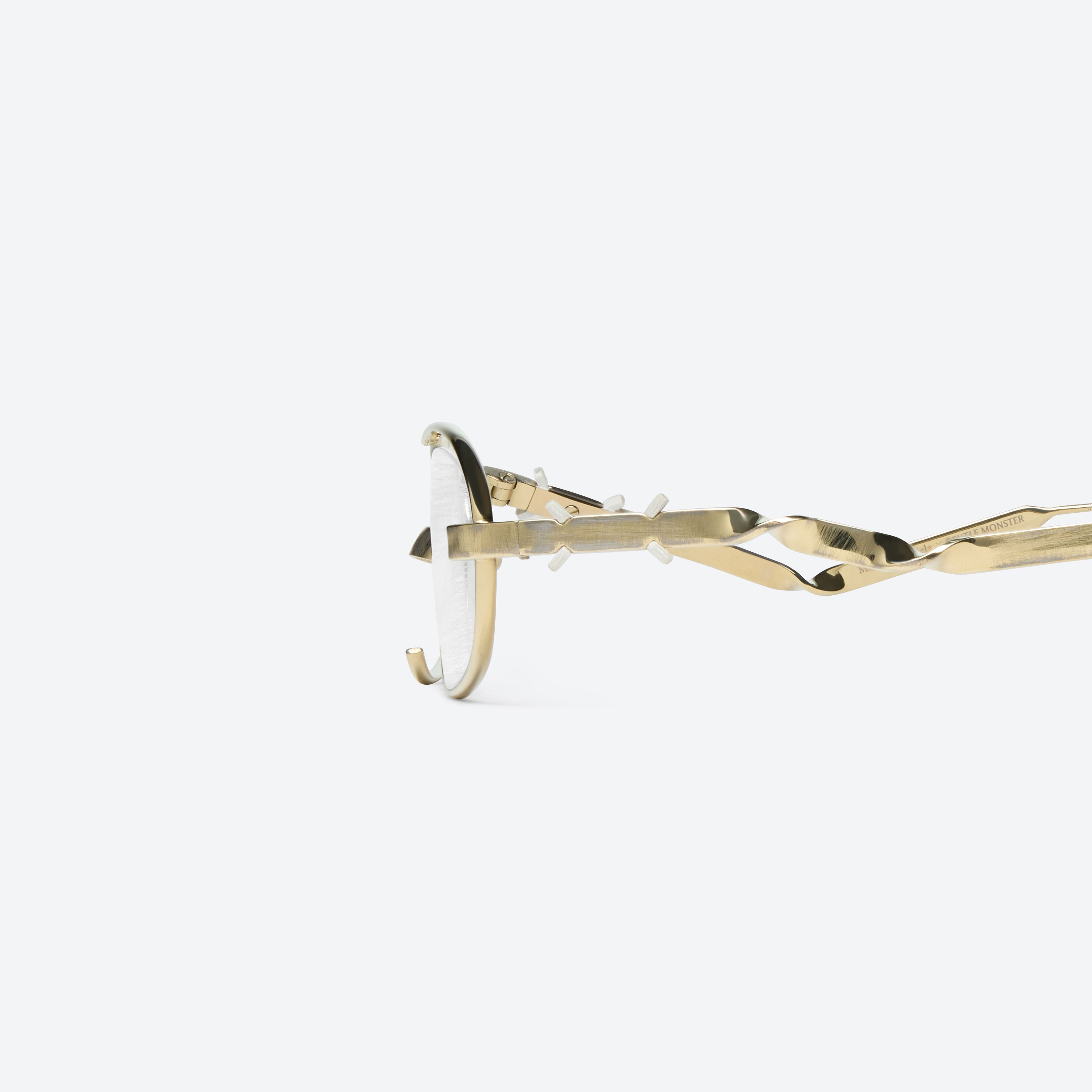 A detailed left view of Gentle Monster Maison Margiela - MM301 039 Gold Metal framed Oval glasses.